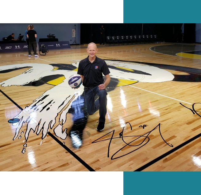 A man kneeling down on the floor holding a basketball.